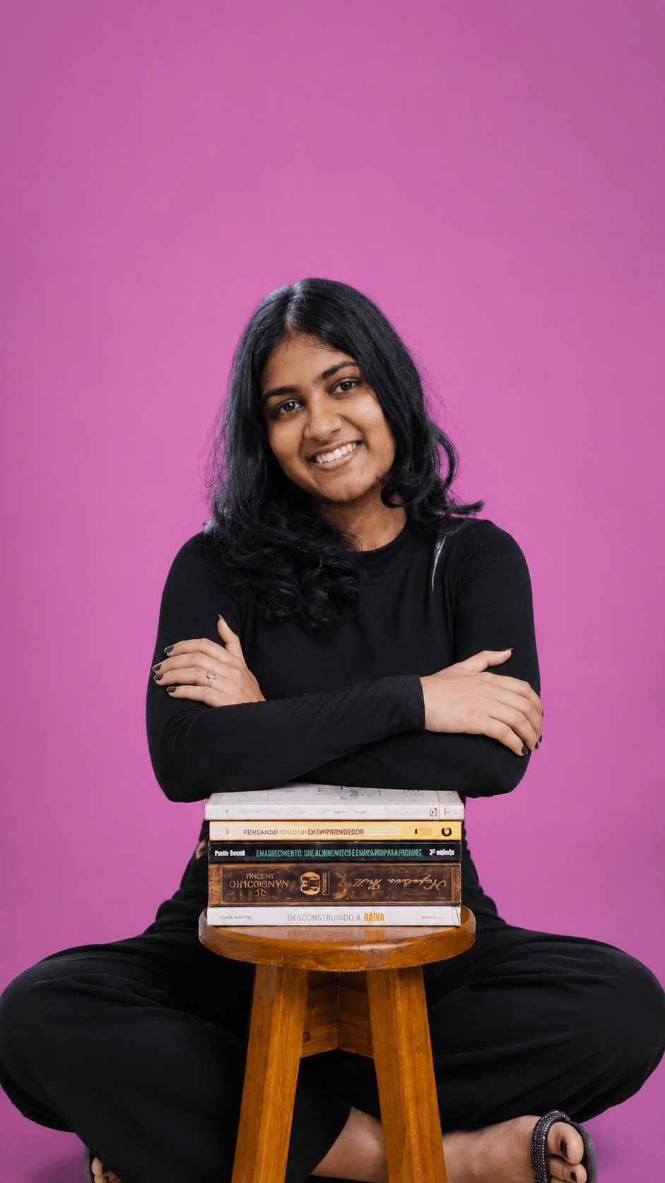 Upeksha sitting with arms crossed over a stack of books